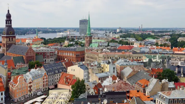 Panorāmas skats uz Rīgas vēsturisko centru un Daugavu mākoņainā dienā.