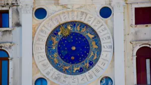 Sena, detalizēta zodiaka pulksteņa ciparnīca uz vēsturiskas ēkas sienas Venēcijā.