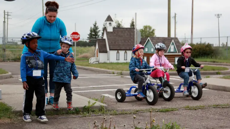 Bērni droši brauc ar trīsriteņiem pa mācību trasi, apgūstot satiksmes noteikumus.