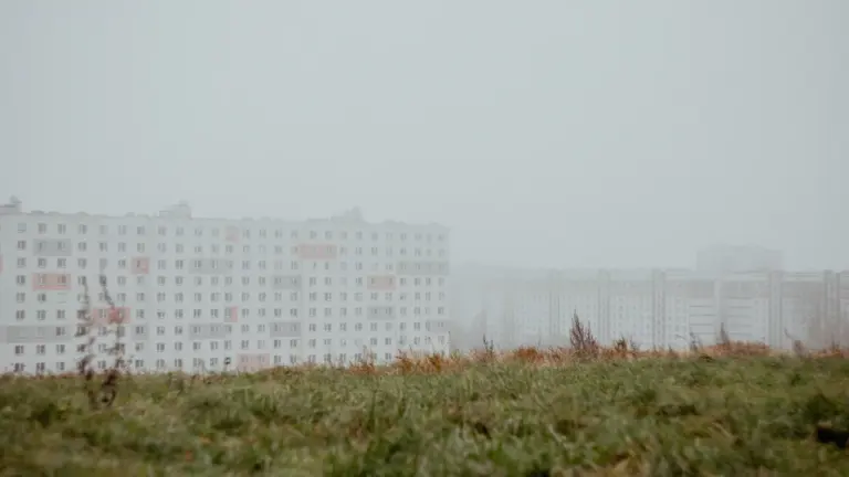 Pelēka un miglaina Rīgas pilsētas ainava ar daudzstāvu namiem rudens sezonā.