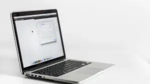 Atvērts klēpjdators uz balta galda, gatavs digitālo abonementu pārvaldīšanai un pārbaudei.